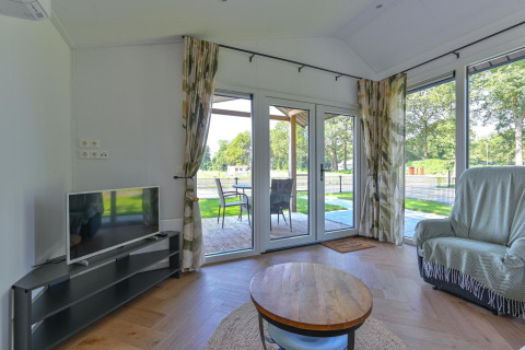 Woonkamer in Luxury lodge - rolstoeltoegankelijk bij Drentse Weelde, Nederland, met tv en terras.