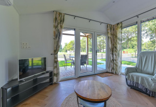 Woonkamer in Luxury lodge - rolstoeltoegankelijk bij Drentse Weelde, Nederland, met tv en terras.