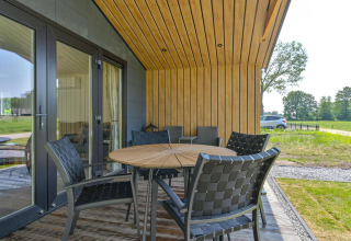 Terraza exterior con mesa redonda de madera y sillas negras en Luxury Lodge - accesible para sillas de ruedas, Drentse Weelde, Países Bajos.