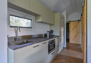 Cocina moderna accesible para sillas de ruedas en Luxury lodge de Drentse Weelde, Países Bajos, con puertas de madera.