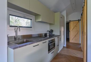 Rolstoeltoegankelijke luxe lodge-keuken bij Drentse Weelde, Nederland, met moderne apparatuur en houten deuren.