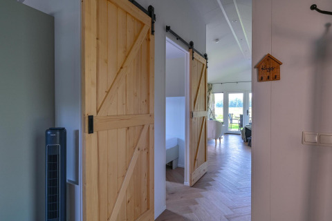 Vista interior de la Luxury lodge en Drentse Weelde con puertas correderas de madera y acceso para sillas de ruedas.
