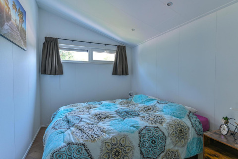 Bright, accessible bedroom with double bed and windows in luxury lodge at Drentse Weelde, Netherlands.