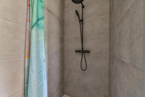 Baño con ducha moderna y cortina verde en Luxury lodge - accesible para sillas de ruedas en Drentse Weelde.