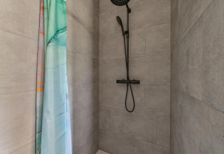 Baño con ducha moderna y cortina verde en Luxury lodge - accesible para sillas de ruedas en Drentse Weelde.