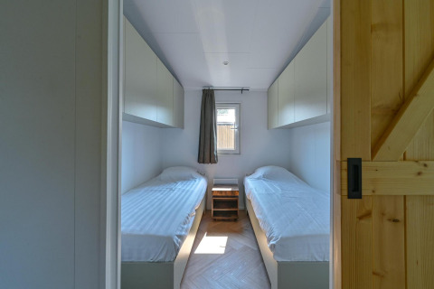 Rolstoeltoegankelijke lodge met twee enkele bedden en kasten bij Drentse Weelde, Nederland.