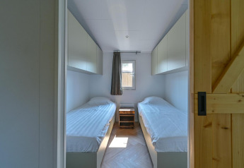 Rolstoeltoegankelijke lodgekamer met twee eenpersoonsbedden en bovenkasten bij Drentse Weelde, Nederland.