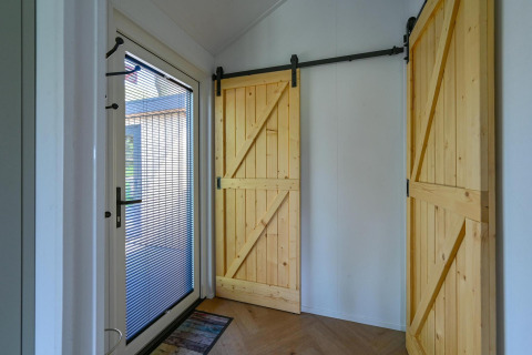 Entrada con puerta de cristal y dos puertas corredizas de madera en Luxury lodge - accesible para sillas de ruedas en Drentse Weelde, Países Bajos.