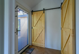 Entrada con puerta de cristal y dos puertas corredizas de madera en Luxury lodge - accesible para sillas de ruedas en Drentse Weelde, Países Bajos.