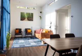 Sala de estar en Nature Lodge en De Thijmse Berg, Países Bajos, con decoración moderna y cortinas azules.
