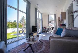 Sala de estar en Nature Lodge en De Thijmse Berg, Países Bajos, con ventanas grandes y decoración moderna.