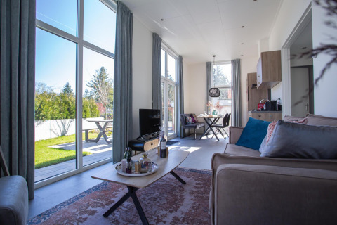 Soggiorno nella Nature Lodge a De Thijmse Berg, Paesi Bassi, con grandi finestre e arredi moderni.