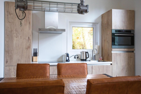 Interno cucina moderna presso Nature Lodge a De Thijmse Berg nei Paesi Bassi con mobili in legno e elettrodomestici.