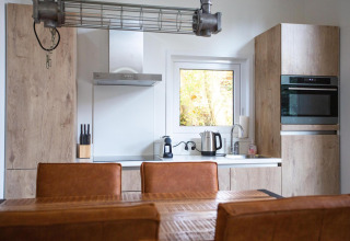 Cocina moderna en Nature Lodge en De Thijmse Berg, Países Bajos, con muebles de madera y electrodomésticos.