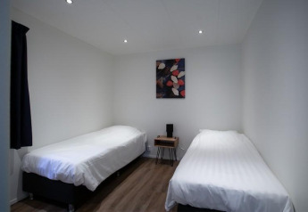 Dos camas individuales con ropa de cama blanca y arte abstracto en la pared en Nature Lodge en De Thijmse Berg.