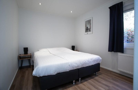 Dormitorio con cama doble, decoración minimalista y ventana grande en Nature Lodge, De Thijmse Berg, Países Bajos.