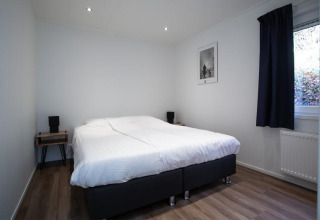 Dormitorio con cama doble, decoración minimalista y ventana grande en Nature Lodge, De Thijmse Berg, Países Bajos.