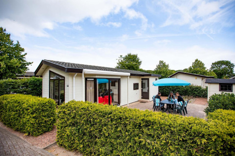 Ferienhaus im EuroParcs Noordwijkse Duinen in den Niederlanden mit Terrasse, Möbeln und Sonnenschirm.