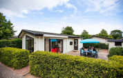 Casa de vacaciones en EuroParcs Noordwijkse Duinen, Países Bajos, con patio, muebles de jardín y sombrilla.