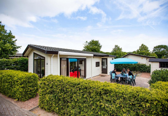 Vakantiewoning op EuroParcs Noordwijkse Duinen in Nederland met terras, tuinmeubelen en parasol.