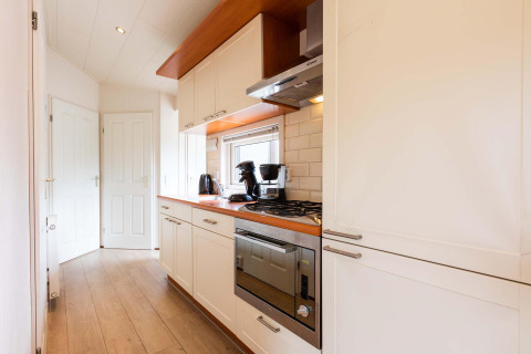 Moderne, smalle keuken in een vakantiehuis aan EuroParcs Noordwijkse Duinen, Nederland, houten werkblad.
