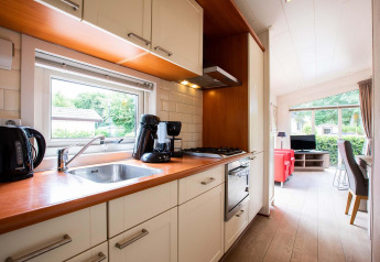 Cuisine moderne et salon d'une maison de vacances à EuroParcs Noordwijkse Duinen, Pays-Bas, en journée.