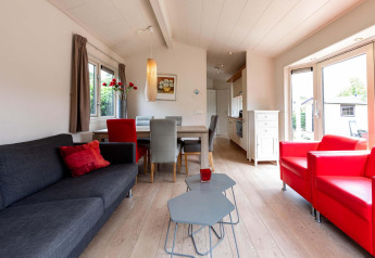 Wohnbereich eines Ferienhauses im EuroParcs Noordwijkse Duinen mit modernen Möbeln und großen Fenstern.