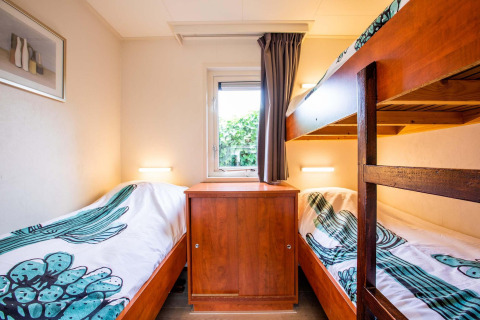 Helles Schlafzimmer im Ferienhaus bei EuroParcs Noordwijkse Duinen mit Etagenbetten und Fenster.