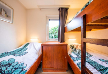 Dormitorio luminoso en casa de vacaciones en EuroParcs Noordwijkse Duinen con literas y ventana.