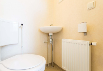Helles Badezimmer mit Toilette, Waschbecken, Heizkörper und Toilettenpapierhalter im Ferienhaus bei EuroParcs Noordwijkse Duinen.