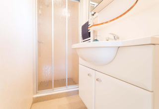 Moderne badkamer met douche en witte lavabo in een vakantiewoning bij EuroParcs Noordwijkse Duinen, Nederland.