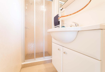 Baño moderno con ducha y lavabo blanco en una casa de vacaciones en EuroParcs Noordwijkse Duinen, Países Bajos.