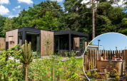 Lodge Veluwe Farm Wellness en Resort Veluwe, Países Bajos, con jacuzzi exterior entre naturaleza y árboles.