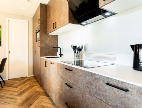 Moderne lodgekeuken met houtmotief vloer, witte werkbladen, ingebouwde oven en zwarte accenten.