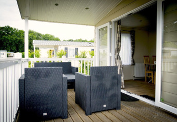 Outdoor terrace with modern black wicker chairs at Forest Lodge in Holiday Park Duinhoeve, Netherlands.