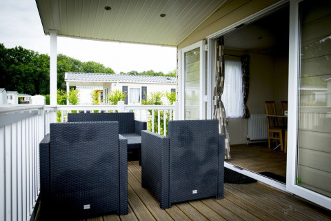 Terrasse extérieure avec fauteuils en osier noir au Forest Lodge du Holiday Park Duinhoeve, Pays-Bas.