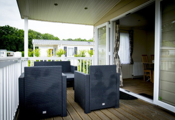 Terraza exterior con sillas negras modernas en Forest Lodge, Holiday Park Duinhoeve, Países Bajos.