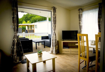 Interior of Forest Lodge tiny house with view of patio and garden at Holiday Park Duinhoeve, Netherlands.