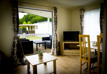 Interno della tiny house Forest Lodge con vista sul patio e giardino a Holiday Park Duinhoeve, Paesi Bassi.