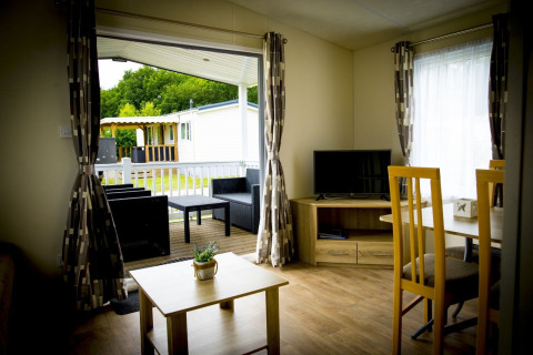 Interno della tiny house Forest Lodge con vista sul patio e giardino a Holiday Park Duinhoeve, Paesi Bassi.