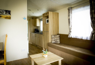 Woonruimte en keuken van Forest Lodge tiny house in Holiday Park Duinhoeve met bank, tafel en modern interieur.