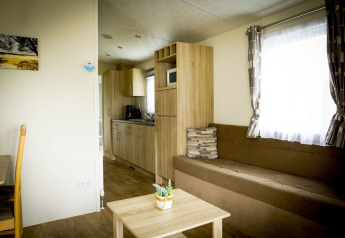 Sala de estar y cocina de la casa pequeña Forest Lodge en Holiday Park Duinhoeve, con sofá y decoración moderna.