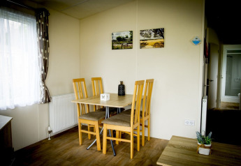 Sala da pranzo al Forest Lodge, Holiday Park Duinhoeve, Paesi Bassi, con tavolo e quattro sedie in legno