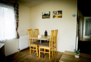 Eethoek in Forest Lodge bij Holiday Park Duinhoeve, Nederland, met tafel en vier houten stoelen bij raam