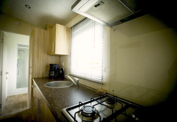 Compact kitchen inside Forest Lodge at Holiday Park Duinhoeve, Netherlands, featuring a gas stove and sink.
