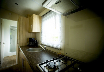 Cocina pequeña en Forest Lodge, Holiday Park Duinhoeve, Países Bajos, con fogón de gas y fregadero.