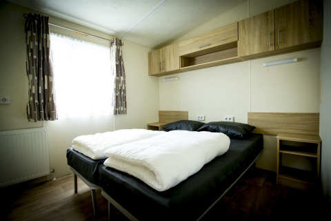 Camera da letto al Forest Lodge, Holiday Park Duinhoeve, Paesi Bassi con letto matrimoniale e mobili in legno.
