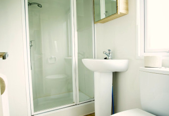 Modern bathroom in Forest Lodge tiny house at Holiday Park Duinhoeve, Netherlands, with shower and wood floor.