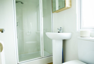 Modern bathroom in Forest Lodge tiny house at Holiday Park Duinhoeve, Netherlands, with shower and wood floor.