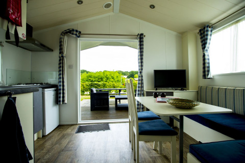 Interior view of Delta Lodge at Holiday Park Duinhoeve, Netherlands, overlooking deck and greenery outside.